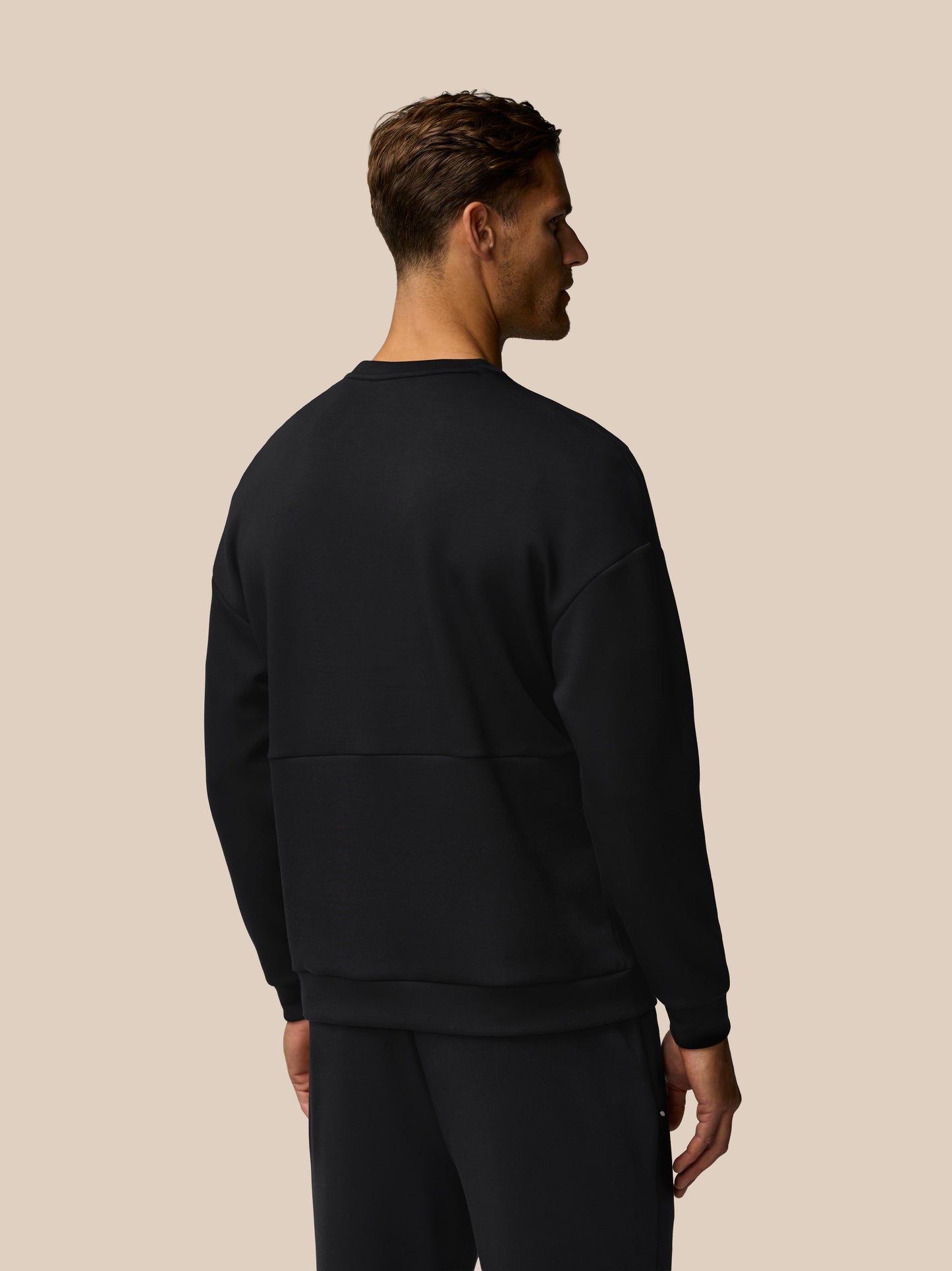 Back view of a man in a black Travel Lifestyle Sweatshirt with dropped shoulders