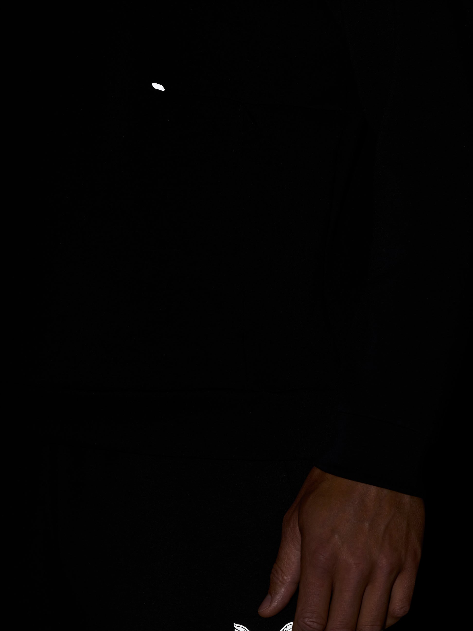 Small white Castore wing logo on black fabric near the hem
