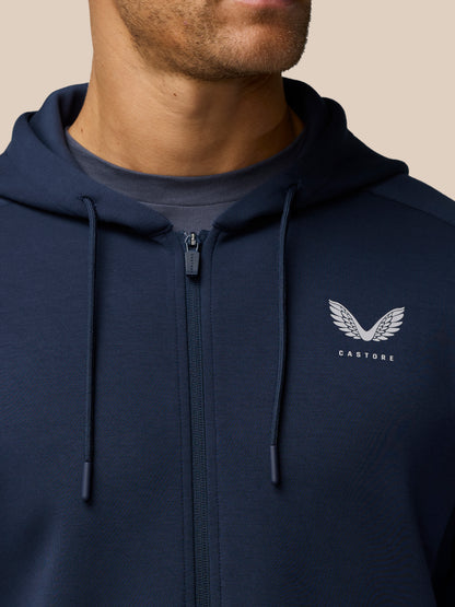 Close-up of navy Travel Lifestyle Zip Hoodie showing zipper drawstrings and Castore logo on the chest