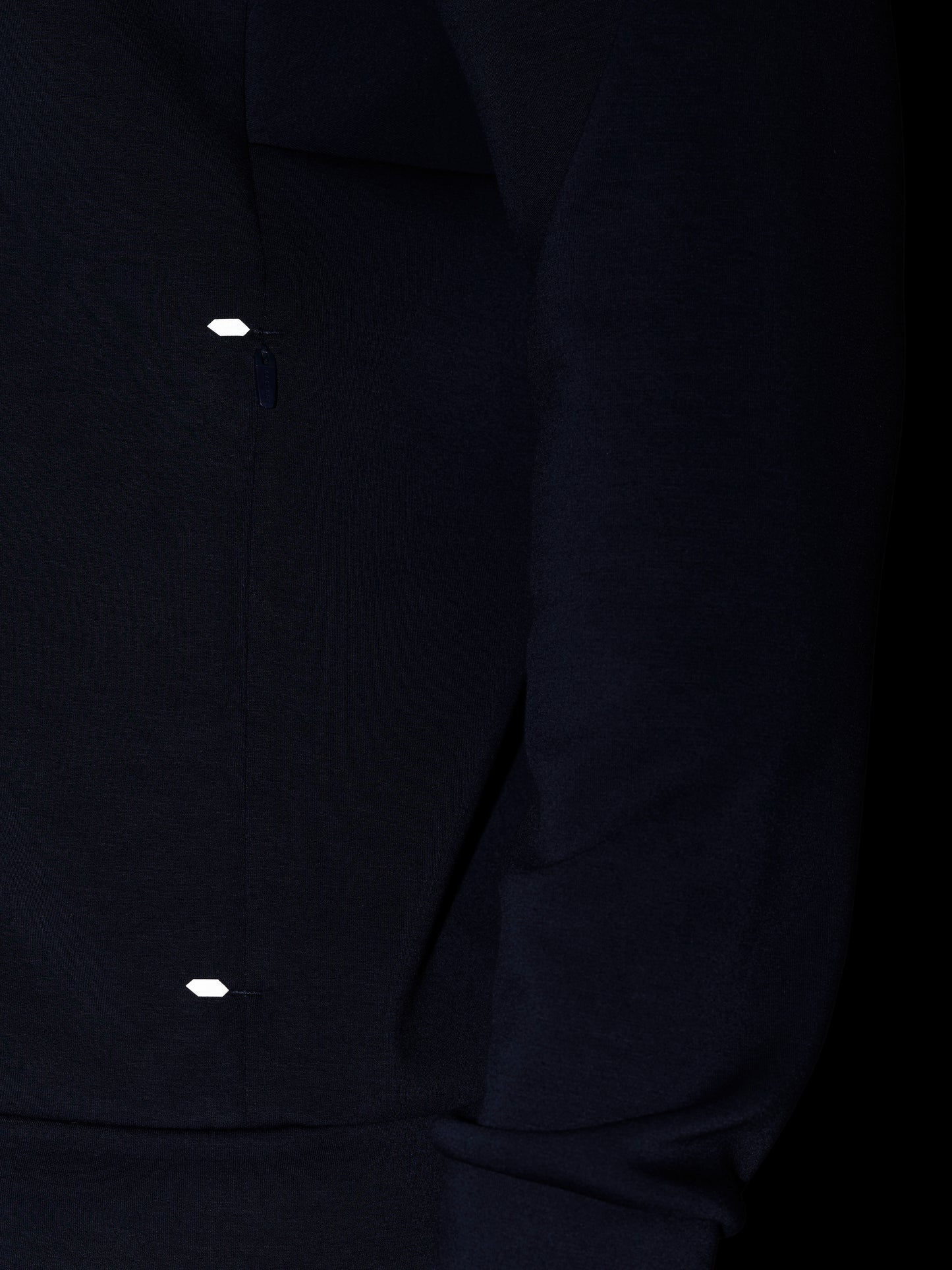Close-up of navy Travel Lifestyle Zip Hoodie fabric with a small reflective tab near the zip.
