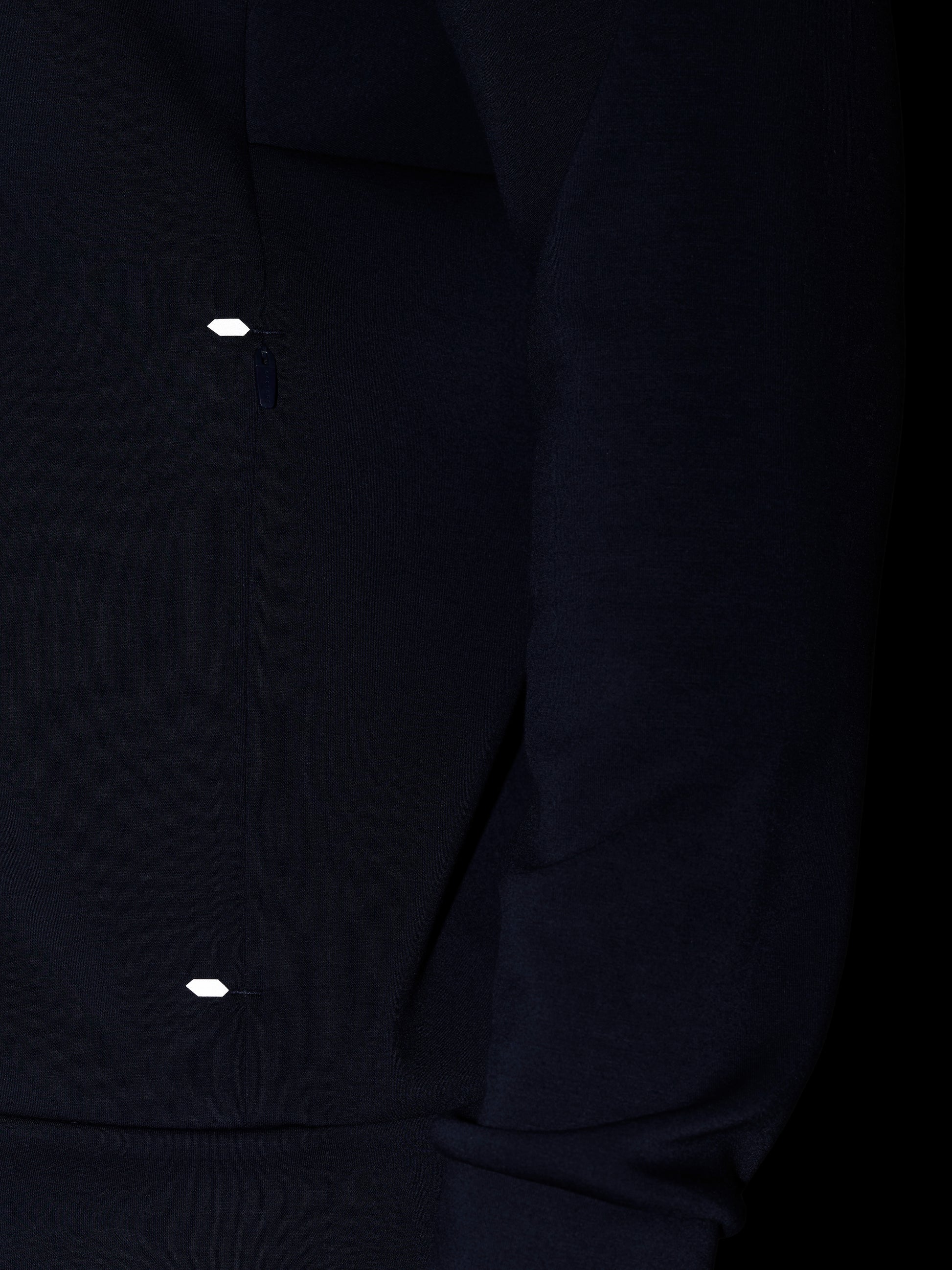 Close-up of navy Travel Lifestyle Zip Hoodie fabric with a small reflective tab near the zip.