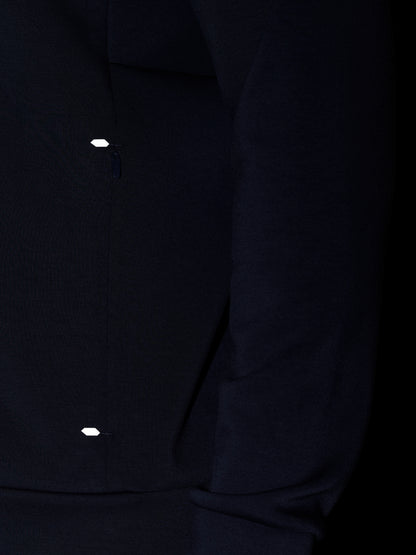 Close-up of navy Travel Lifestyle Zip Hoodie fabric with a small reflective tab near the zip.