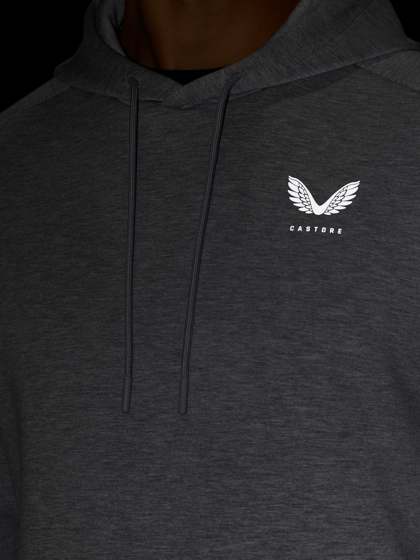 Close up of dark grey hoodie chest area with drawstrings and white Castore logo on the left chest