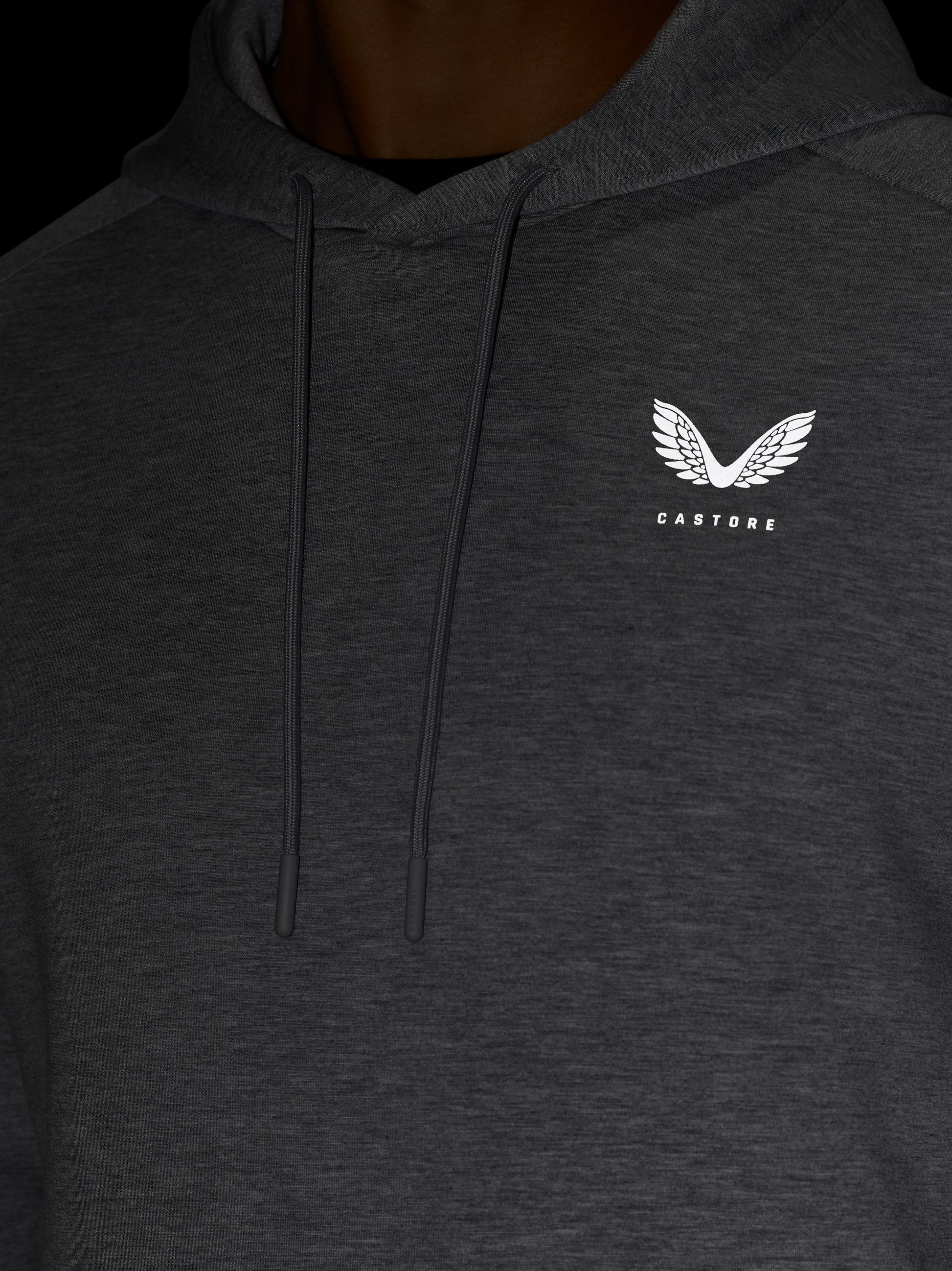 Close up of dark grey hoodie chest area with drawstrings and white Castore logo on the left chest