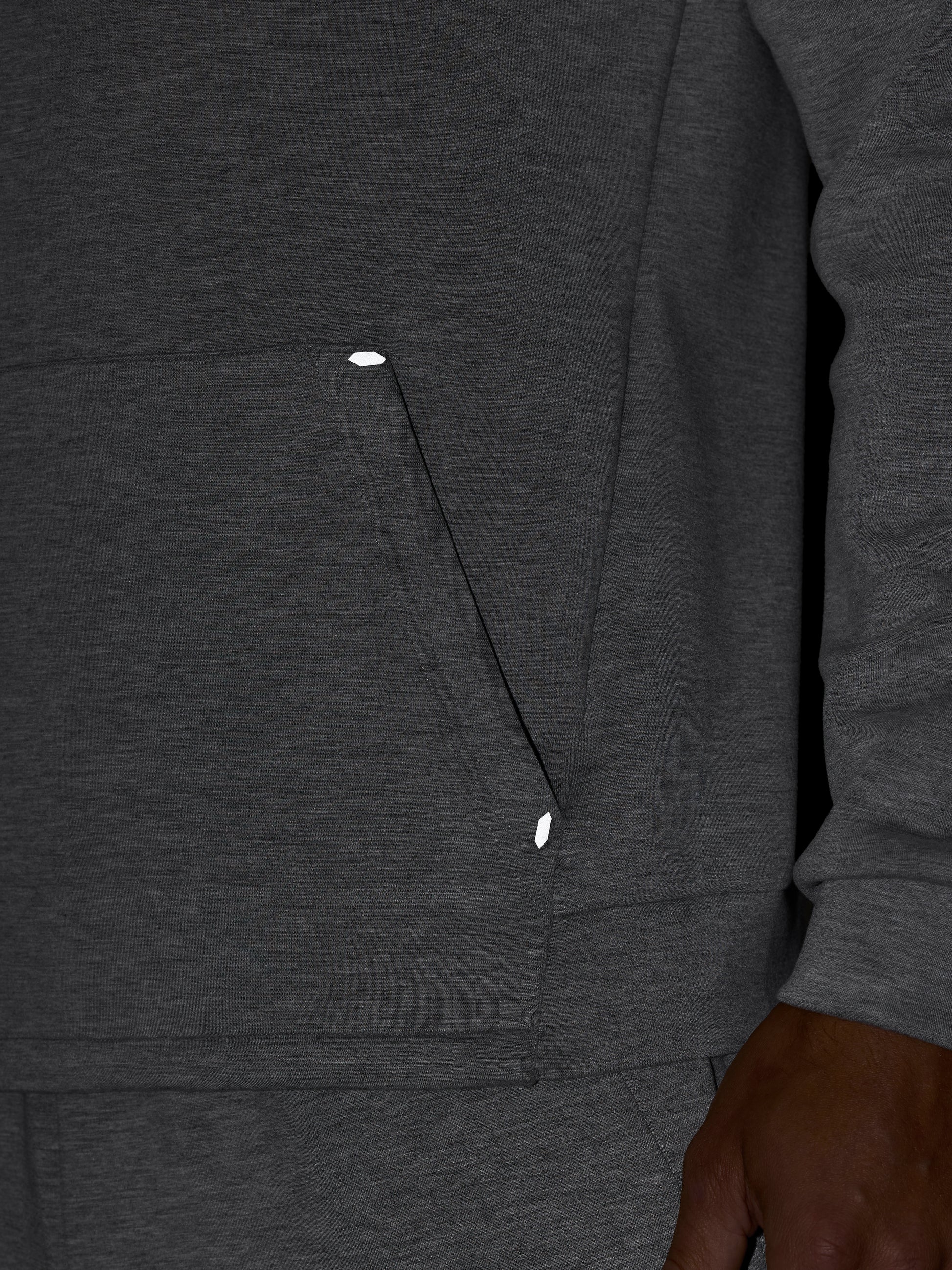 Detail of dark grey hoodie showing front pocket seam and textured fabric