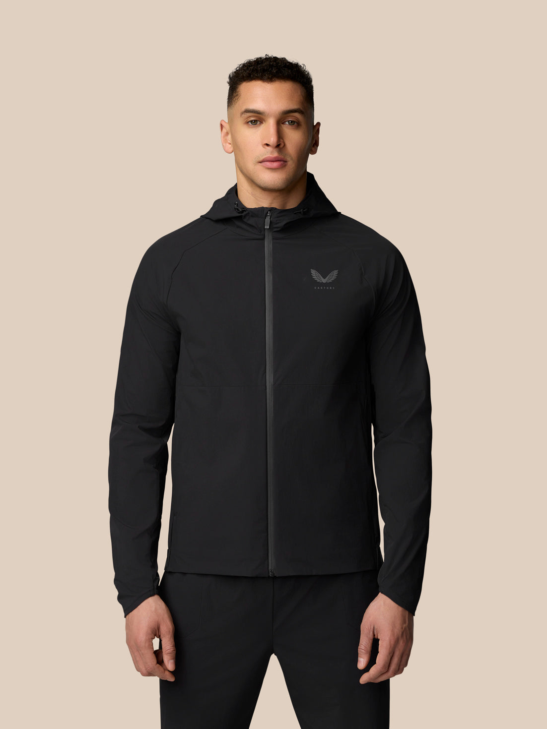Man wearing black Adapt Training Wind Jacket with hood and front zipper.