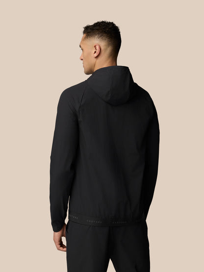 Back view of man in black Adapt Wind Jacket with hood and CASTORE branded waistband