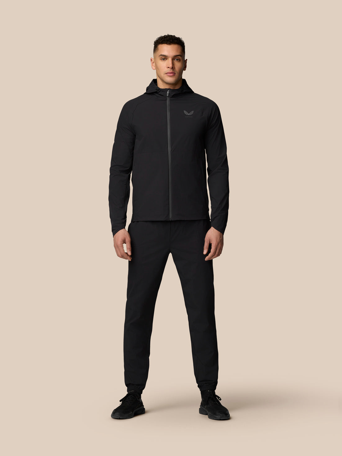Full body shot of a man in black Adapt Training Wind Jacket with hood.