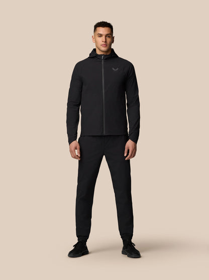 Full body shot of a man in black Adapt Training Wind Jacket with hood.