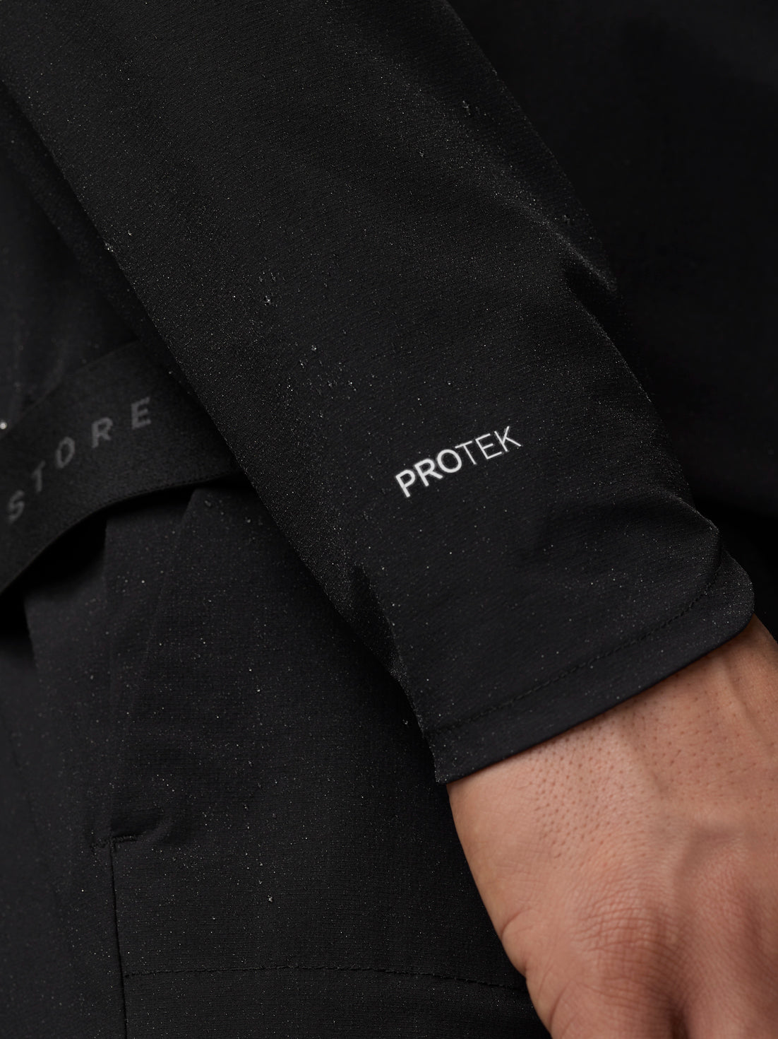 Close-up of black Adapt Training Wind Jacket sleeve with ProTek label
