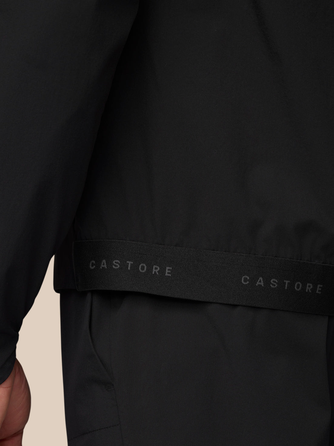 Hem detail of black wind jacket with Castore branded strap