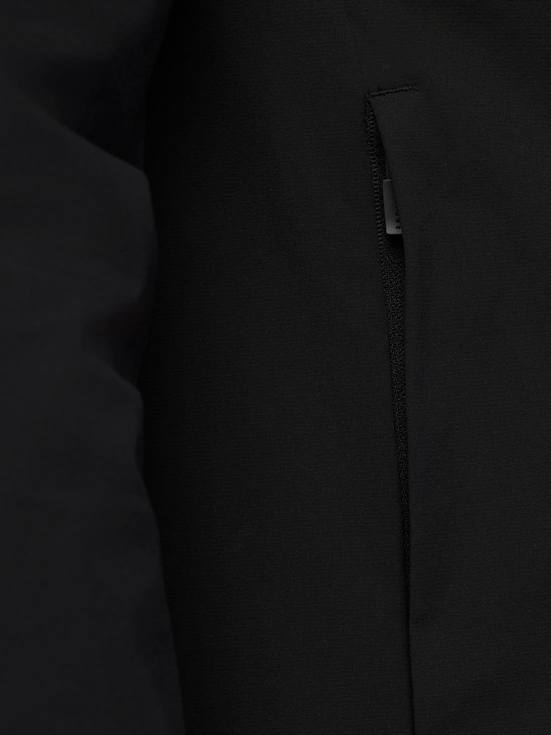 Close up of black Adapt Training Wind Jacket fabric with a concealed zip pocket.