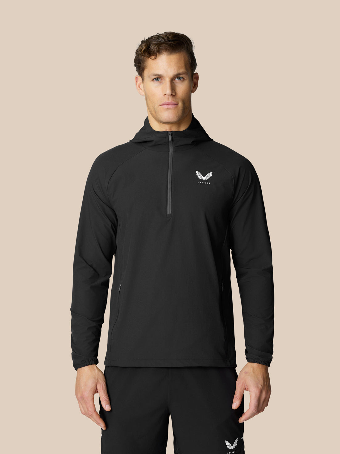 Man in black Flow Training Hoodie with half zip and white Castore logo on chest