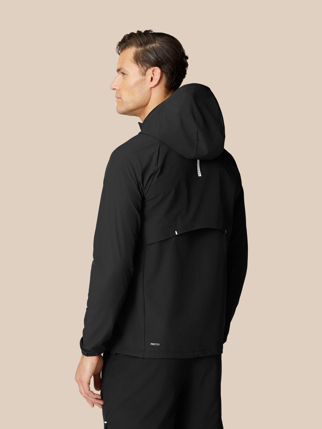 Side profile of a man wearing a black Flow Training Hoodie with hood and vented back panel