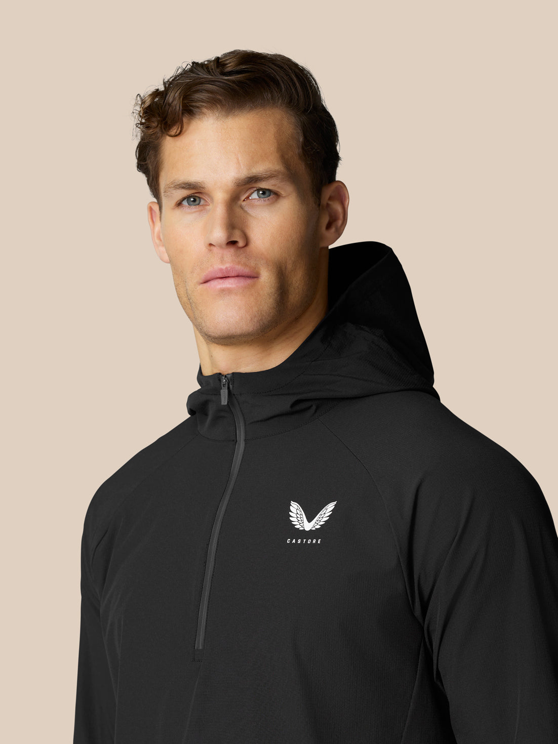 Male model wearing black Flow half zip Hoodie front view with hood and chest logo.