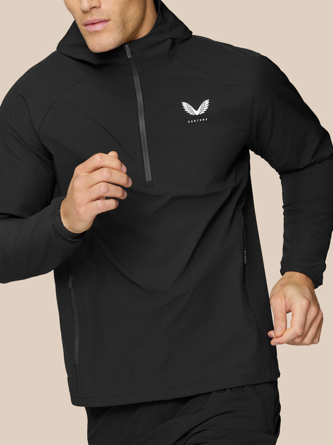 Close-up of a man in a black Flow Training Hoodie showing the half zip chest and small logo