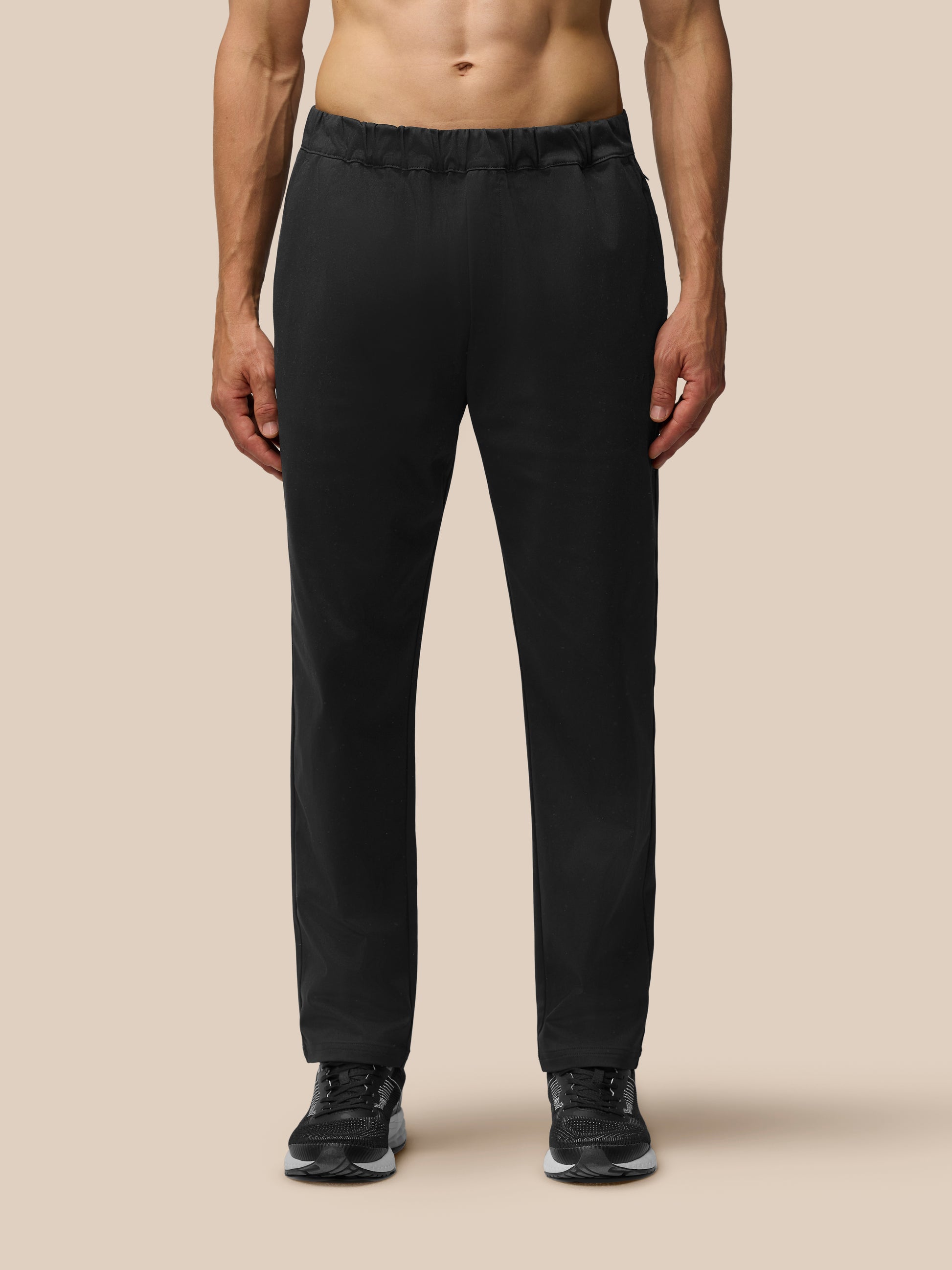 Back view of a man wearing black tailored trousers with elastic waist and back yoke zipped pocket