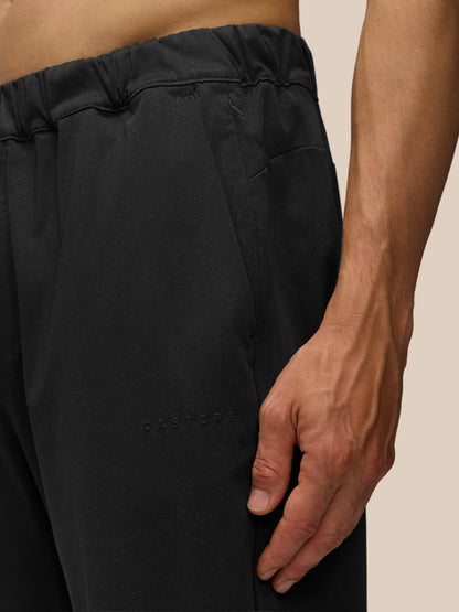 Close up of the waistband area on black tailored trousers showing elastic band and embossed Castore branding near the hem.