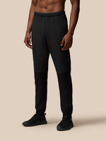 Male model wearing black Flex Winterised Woven Joggers with elastic waistband and zipped pockets