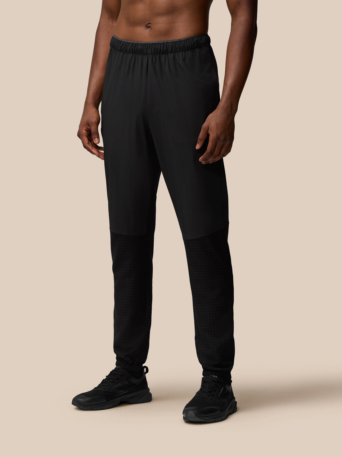 Male model wearing black Flex Winterised Woven Joggers with elastic waistband and zipped pockets
