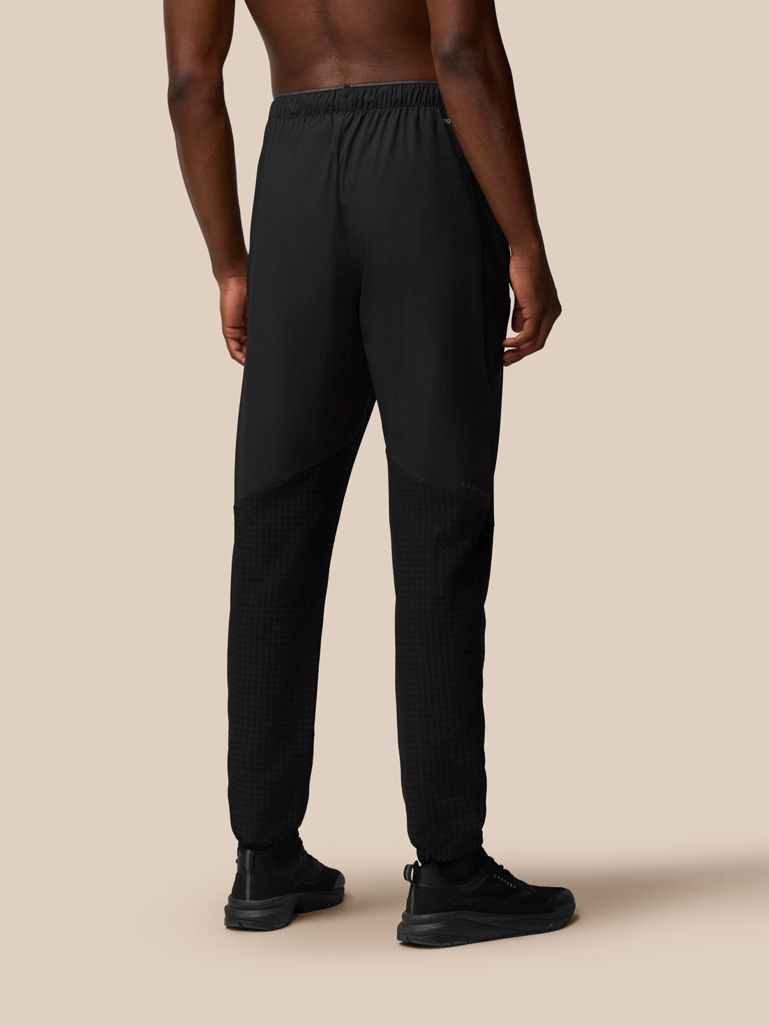 Back view of a man in black Flex Winterised Woven Joggers showing elastic waist and tapered legs