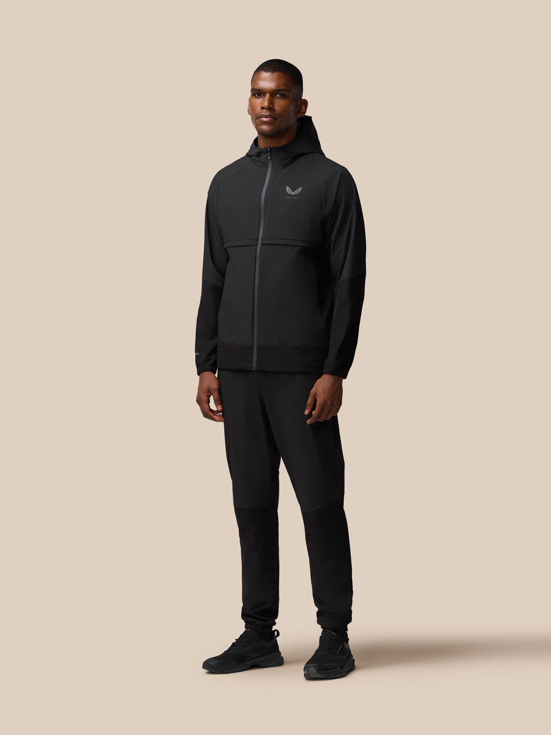 Male model wearing black Flex Winterised woven hooded jacket with zip and matching joggers