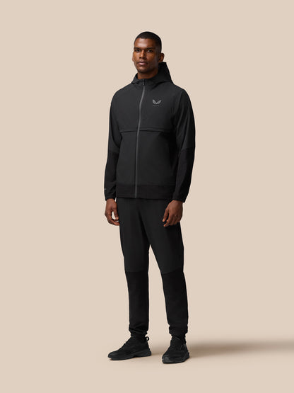 Male model wearing black Flex Winterised woven hooded jacket with zip and matching joggers