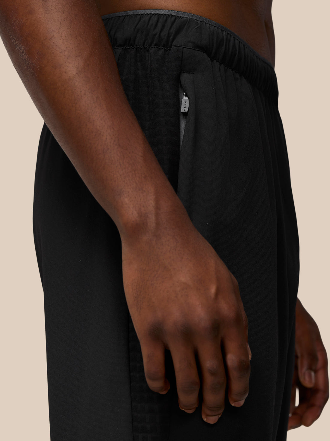 Close-up of black Flex Winterised Woven Joggers showing a side zip pocket and fabric texture.