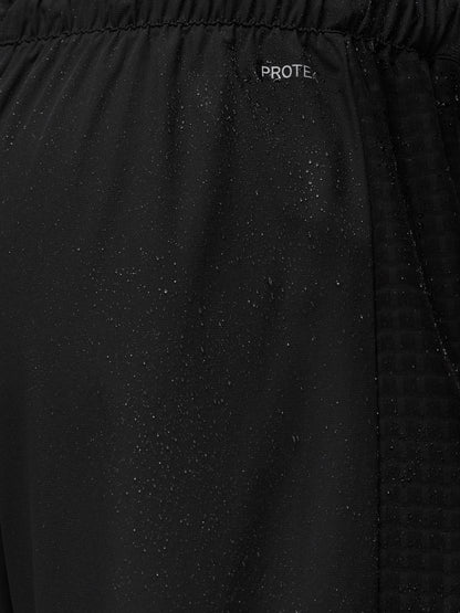 Close-up of black jogger fabric with ProTek branding and water droplets showing water resistance