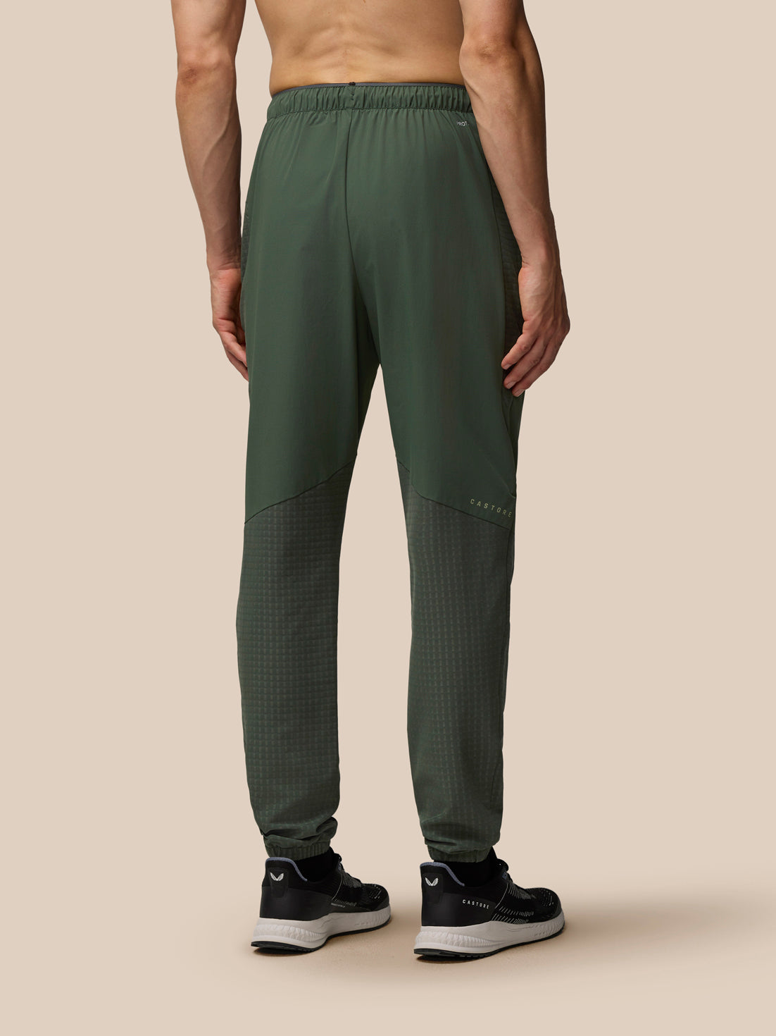 Rear view of a man wearing dark green Flex Winterised Woven Joggers with elastic waistband and tapered cuffs.
