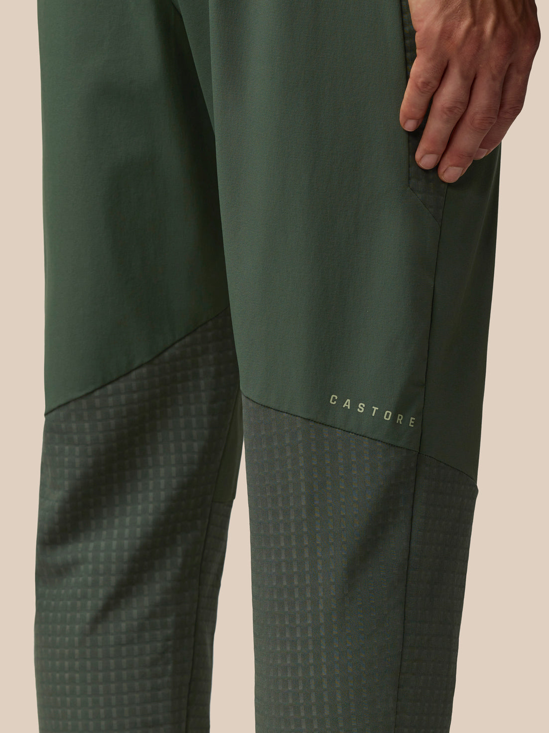 Close-up of dark green Flex Winterised Woven Joggers leg showing textured lower panel and Castore branding.