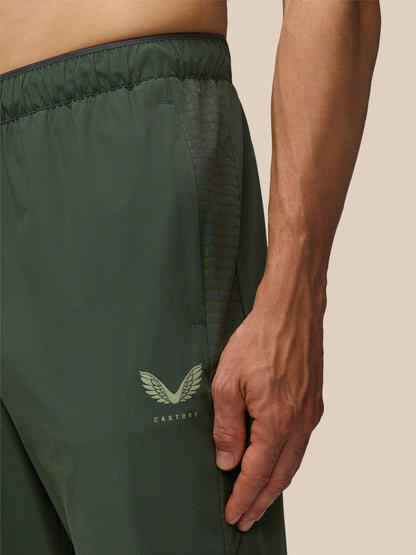 Close-up of the waistband and leg showing a textured panel and Castore logo on the dark green joggers.