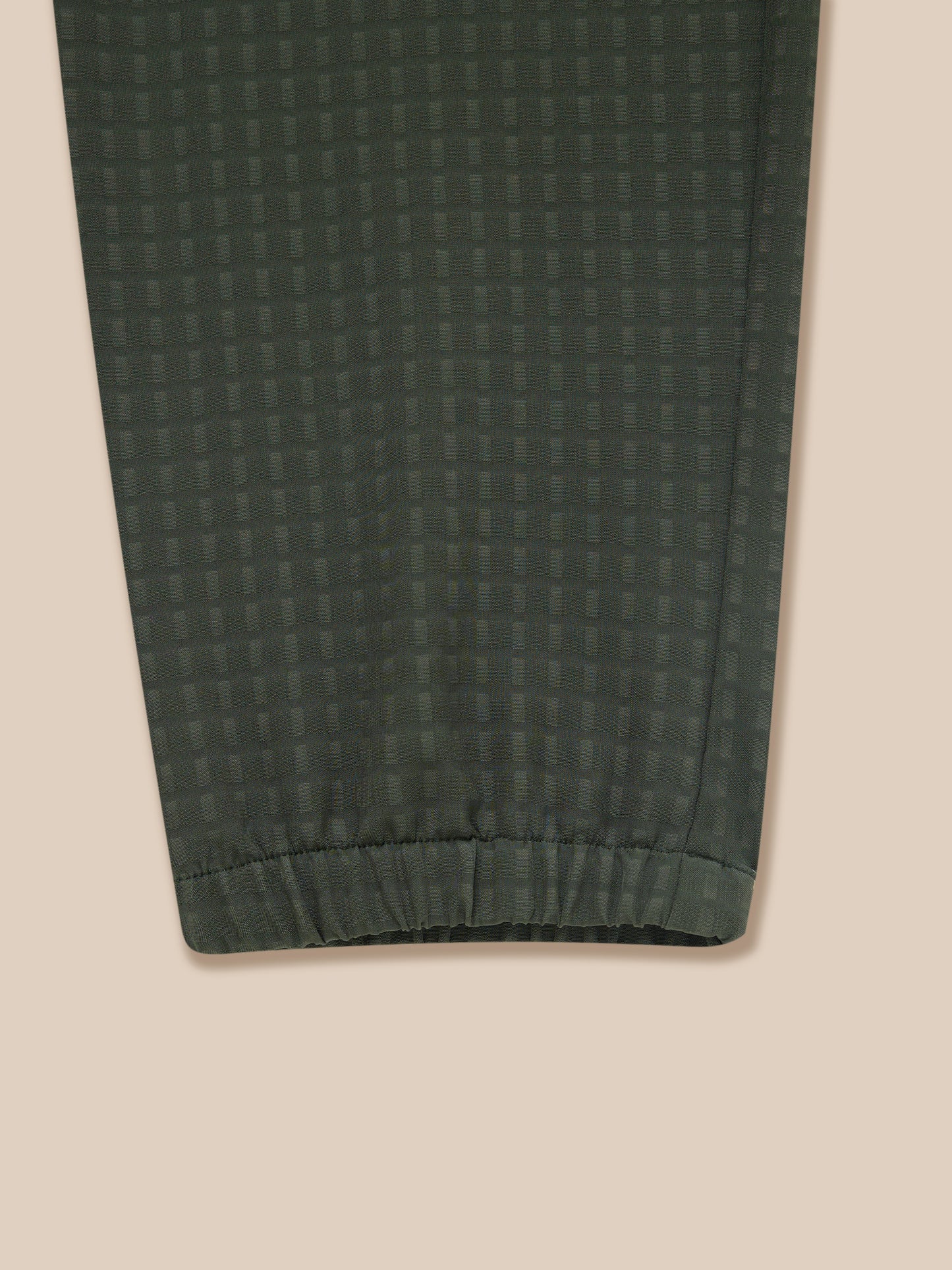 Close-up of dark green woven fabric on Flex Winterised Woven Joggers showing a subtle grid pattern and elastic cuff