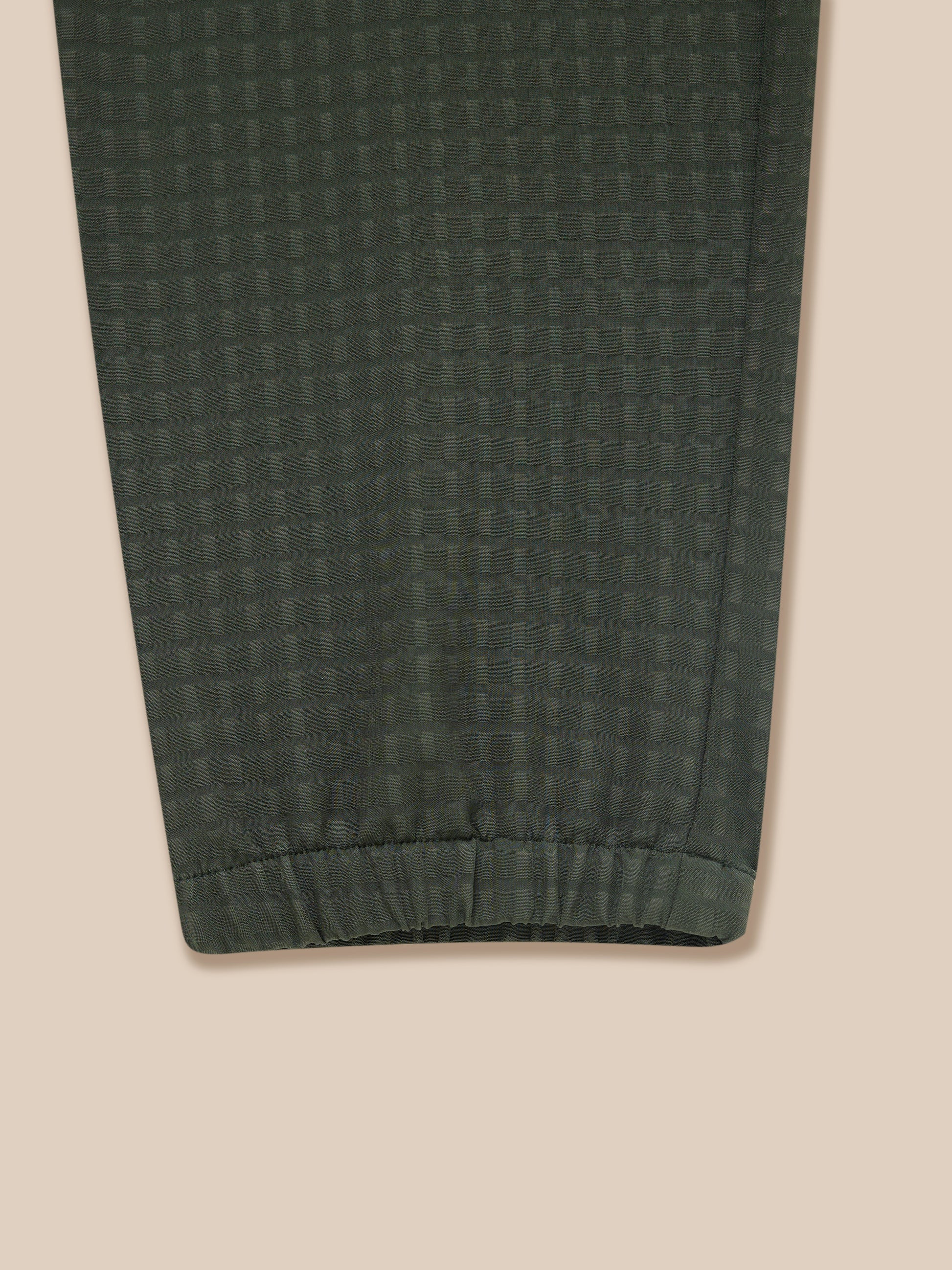 Close-up of dark green woven fabric on Flex Winterised Woven Joggers showing a subtle grid pattern and elastic cuff