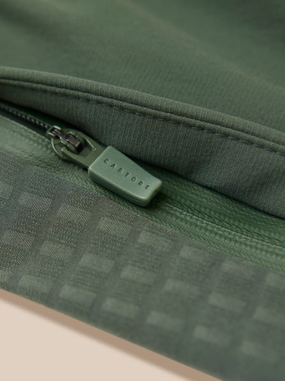 Close up of dark green woven fabric with a green zipper pull featuring Castore branding
