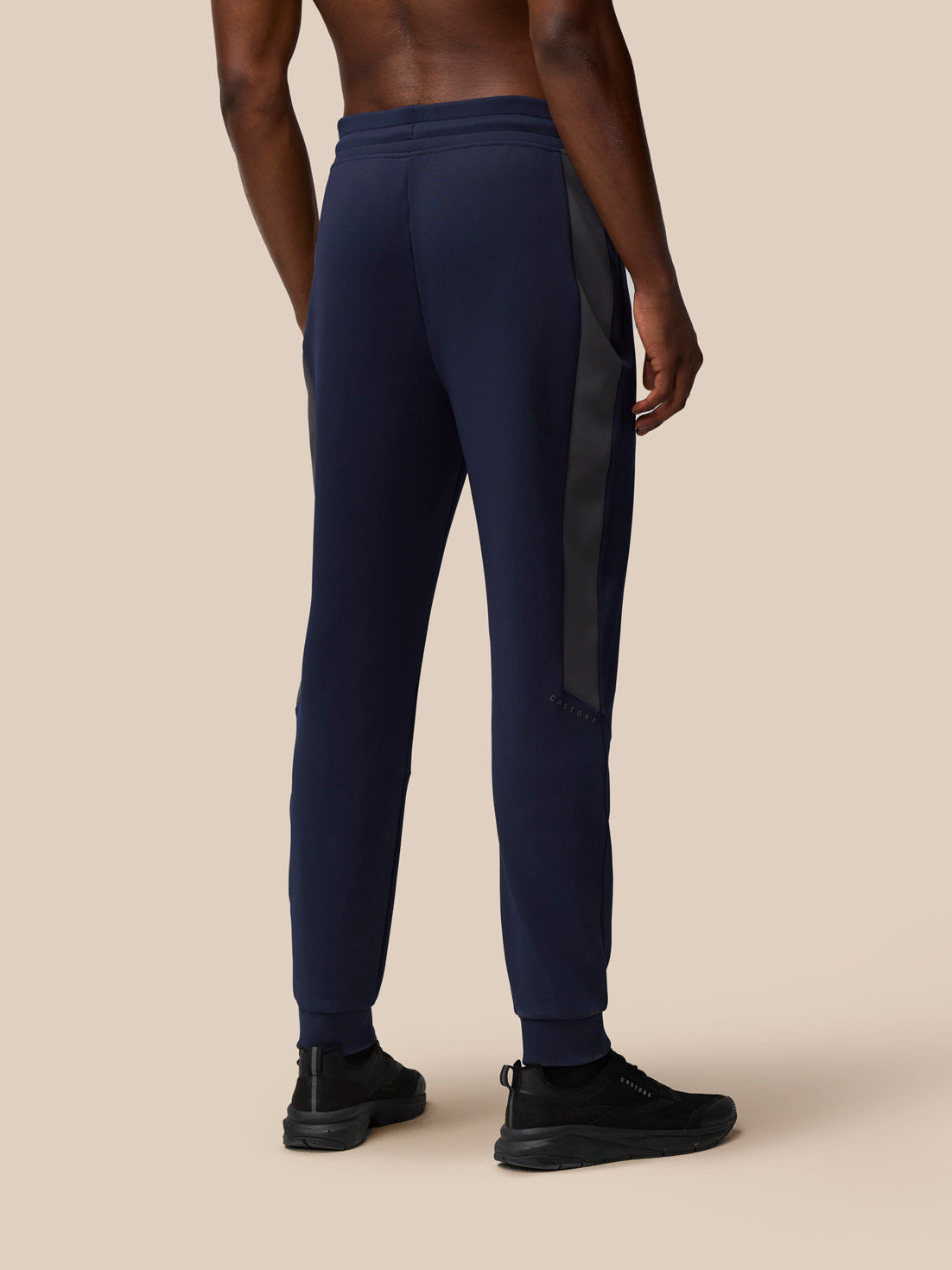 Back view of navy Flex Lifestyle Thermo Pant with a light gray side panel and Castore branding on the left leg.