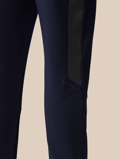 Close-up of navy pant leg with a dark side stripe and Castore branding near the knee.