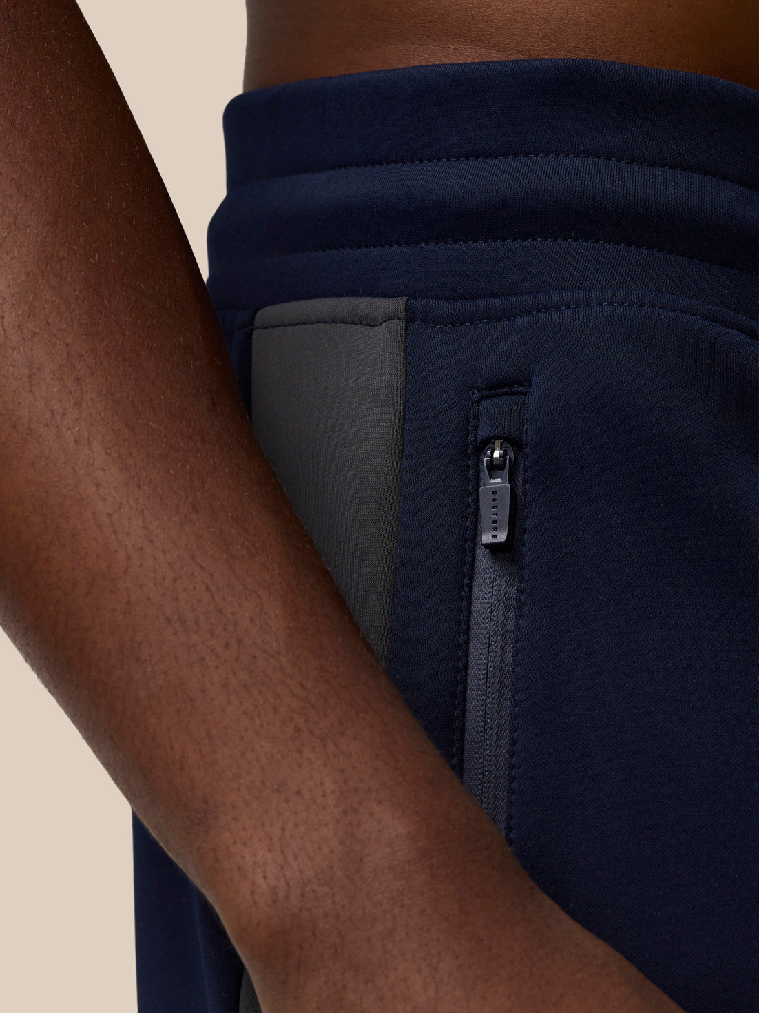 Close up of navy Flex Thermo Pant waist showing a zipped side pocket and Castore branding