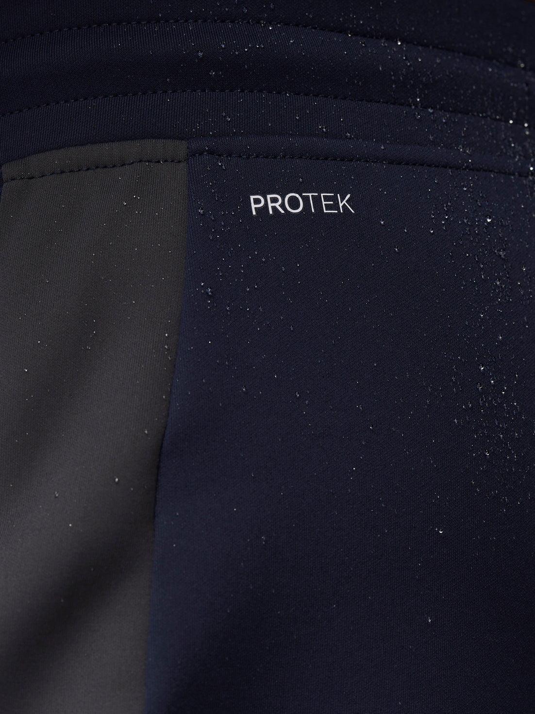 Close-up of navy fabric with water droplets and PROTEK branding.