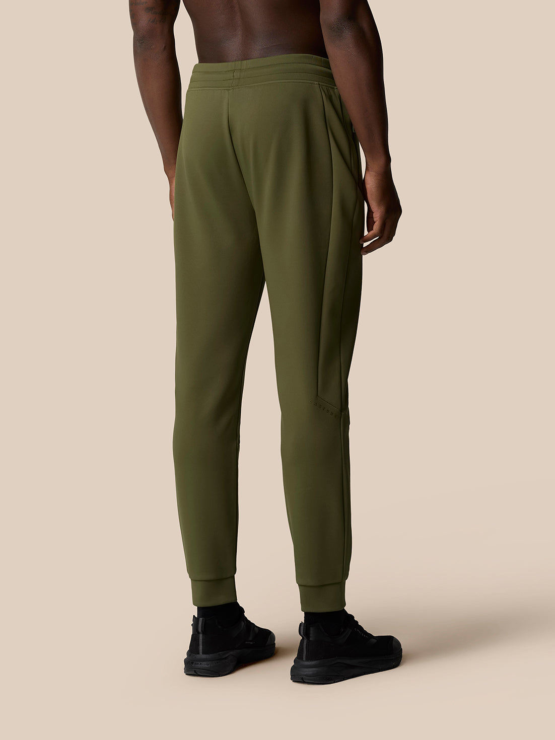 Back view of a male model wearing olive green Flex Thermo Pant with cuffed ankles and Castore logo on the left leg.