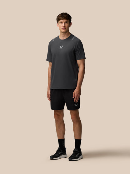 Model wearing Apex Training 6 inch Shorts in black with logo on the left leg against a beige background.