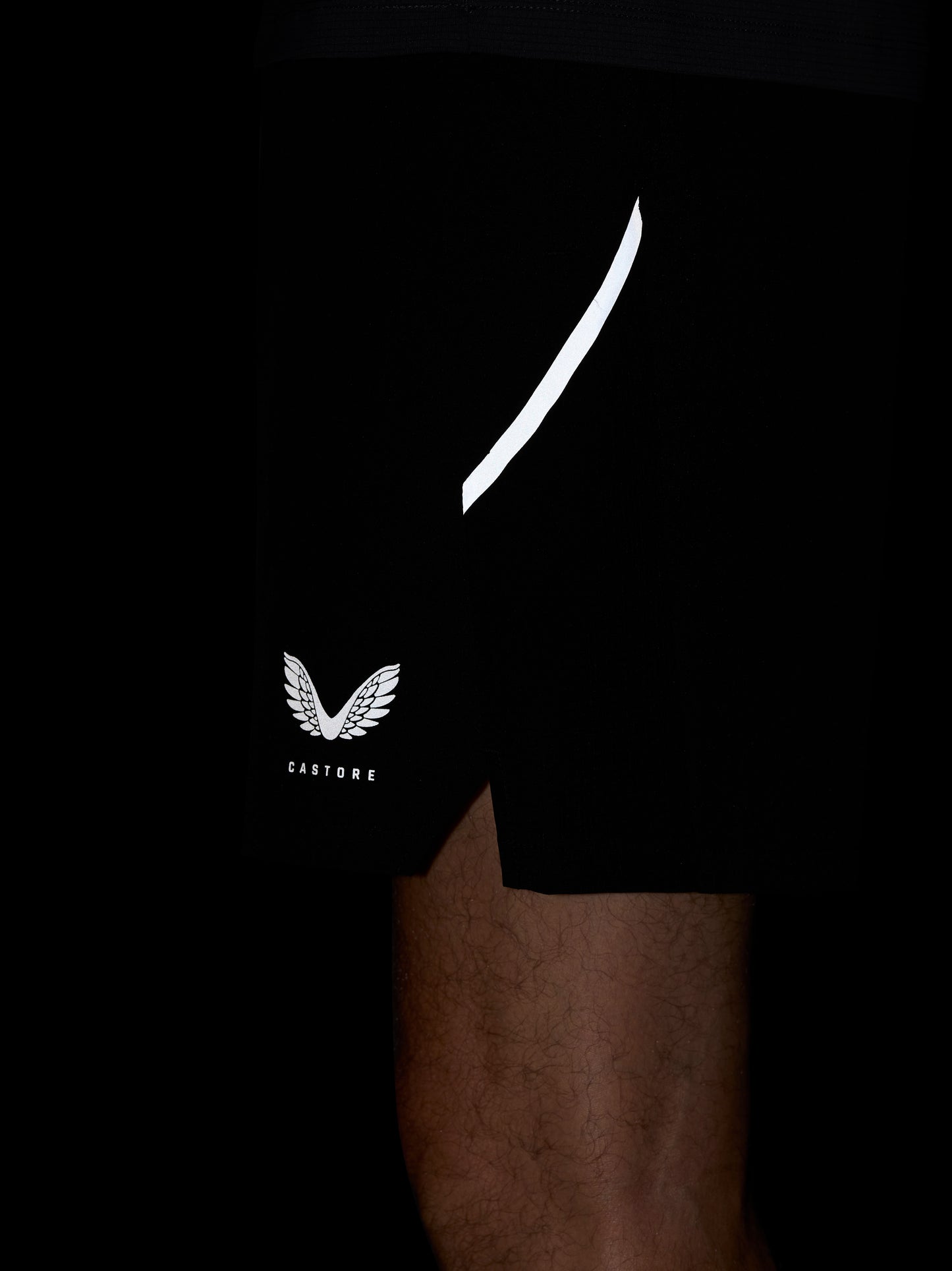 Close-up of black Apex Training 6-inch shorts showing a white curved side stripe and Castore logo on the leg