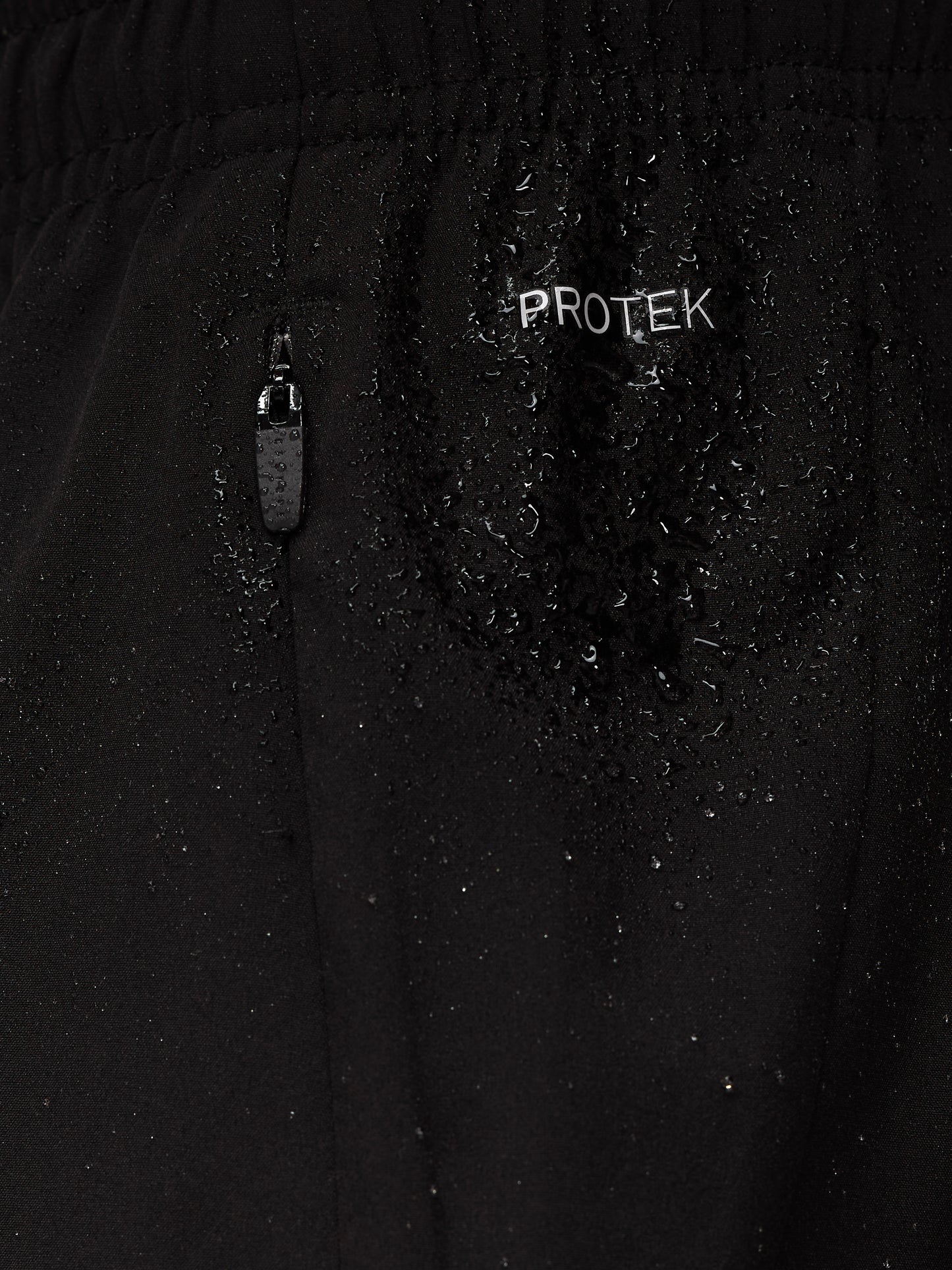 Close up of black Apex Training 6in shorts fabric with ProTek branding and a zipper pocket with water droplets