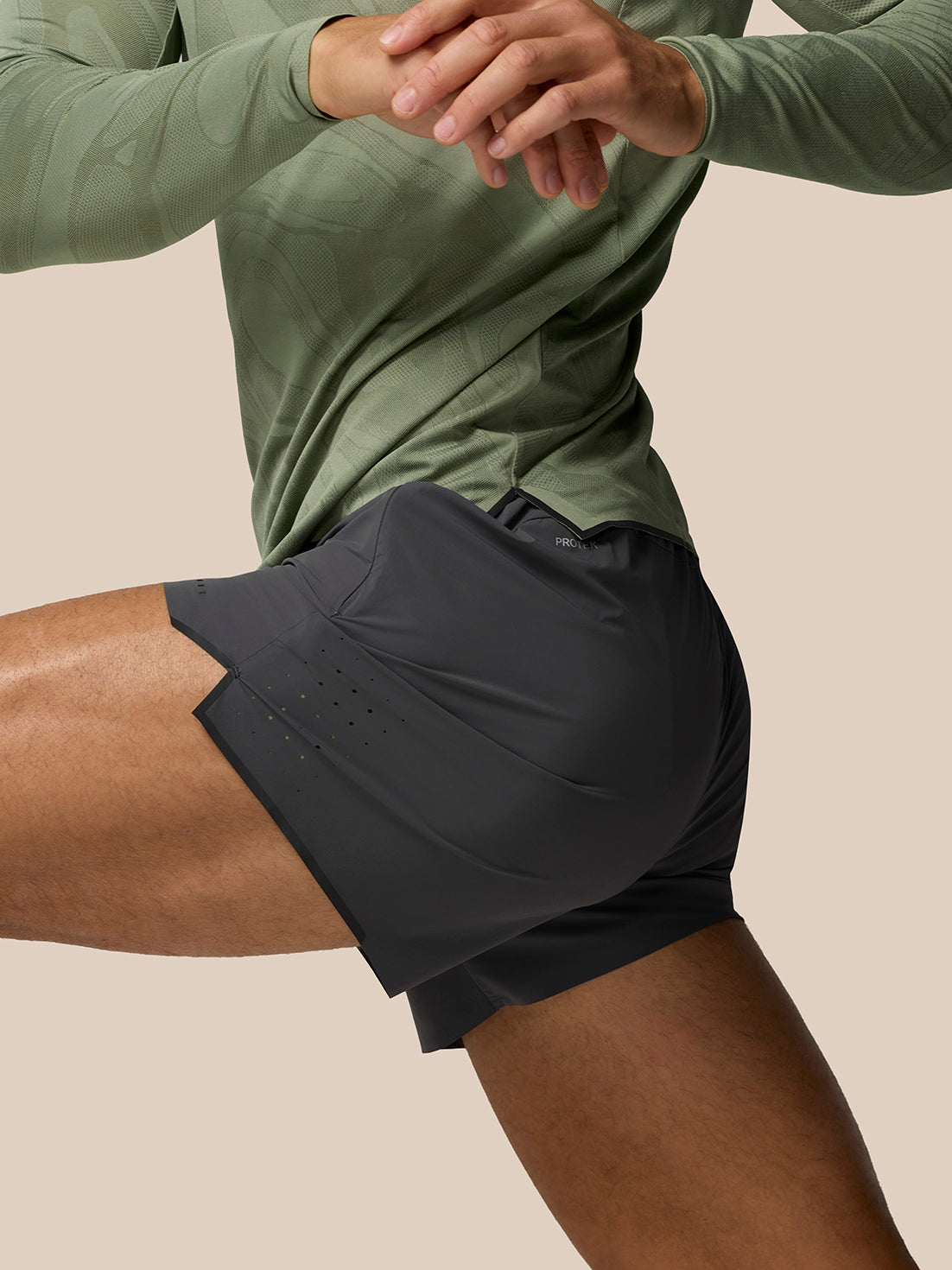Side view of a person wearing dark gray Zone Training LVS 5 inch shorts with perforated vents and a small reflective logo.