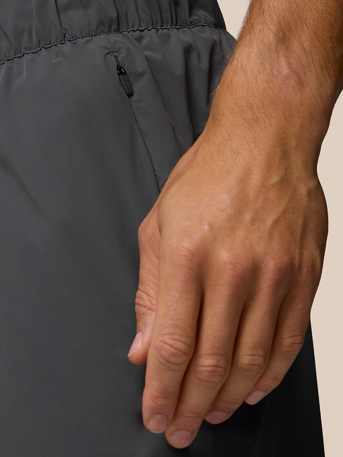 Close-up of zipped pocket on dark Zone Training LVS 5 inch shorts with a hand resting beside the pocket.