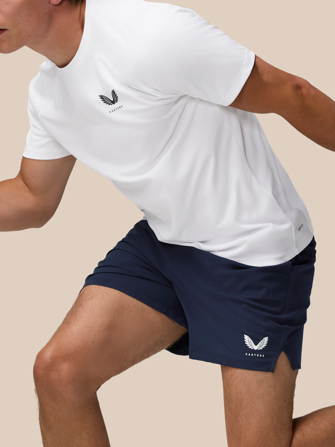 Athlete in navy Adapt Training 5 Inch Shorts with a white top, featuring the Castore wing logo on the leg.