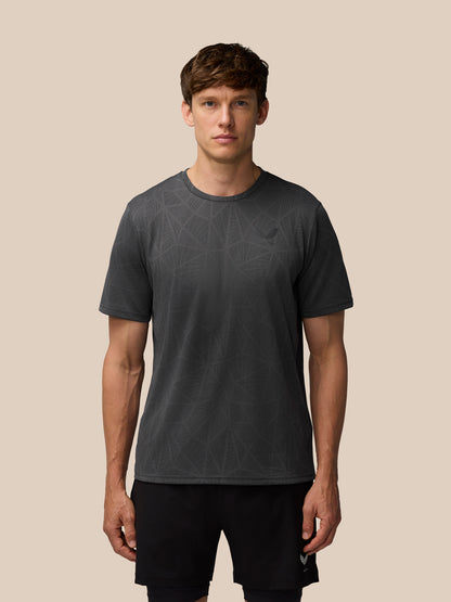 Male model wearing a dark gray Flow Training Engineered Knit T Shirt with subtle geometric pattern