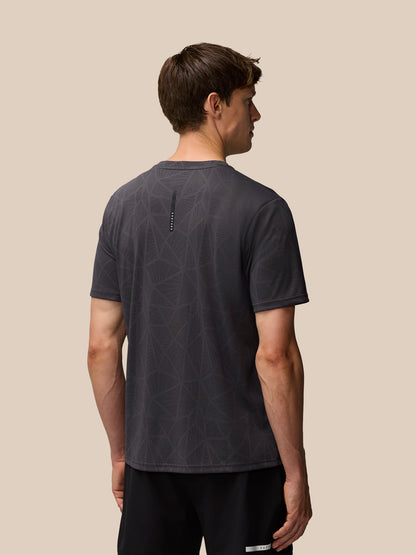 Back view of a man wearing Flow Training Engineered Knit T-Shirt in dark gray with branded back neck tape and geometric print
