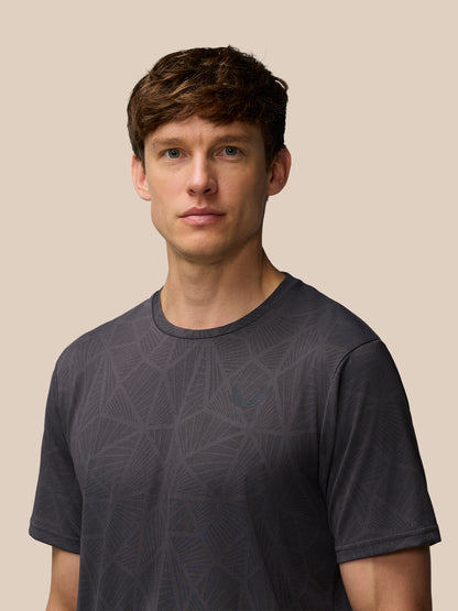 Man wearing Flow Training Engineered Knit T-Shirt in dark gray with geometric knit pattern and Castore logo on chest