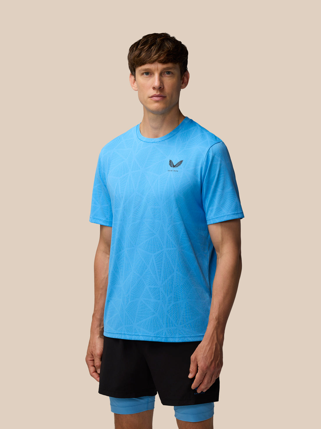 Male model wearing cool blue Flow Training Engineered Knit T Shirt with subtle knit pattern and Castore logo on the chest